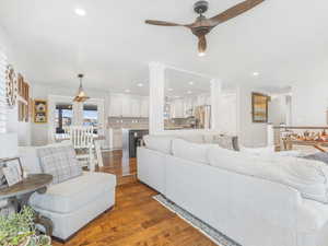 Living room with wood-type flooring, ornate columns, and ceiling fan