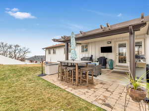 Rear view of property with a lawn and a patio