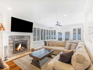 Living room with ceiling fan, a stone fireplace, french doors, and light hardwood / wood-style flooring