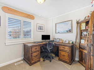 Carpeted home office with crown molding