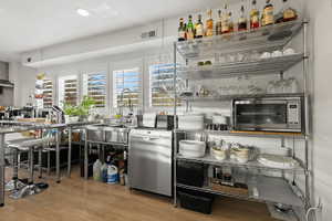 Bar with dishwasher, light wood-type flooring, and sink