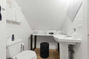 Bathroom featuring lofted ceiling, toilet, and wood-type flooring