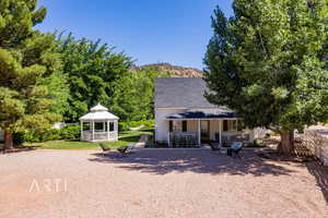 View of front facade with a gazebo, a mountain view, covered porch, and a front yard