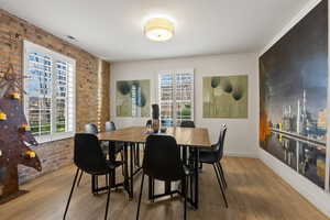 Dining room with hardwood / wood-style floors and brick wall