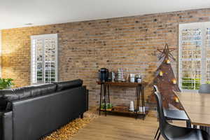 Living room with brick wall and light hardwood / wood-style flooring