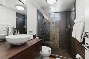 Bathroom featuring hardwood / wood-style floors, toilet, a shower with shower door, and sink