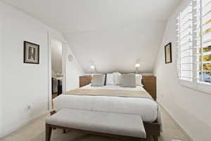 Bedroom with light carpet and lofted ceiling