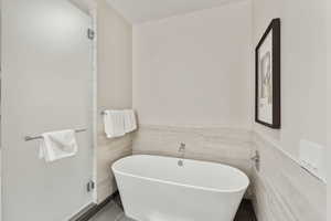 Bathroom featuring tile patterned floors, a tub, and tile walls