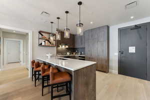 Kitchen featuring pendant lighting, a breakfast bar, sink, tasteful backsplash, and dark brown cabinetry