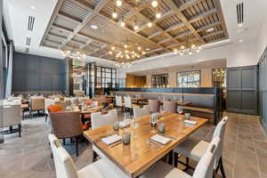 Tiled dining room featuring coffered ceiling and a high ceiling