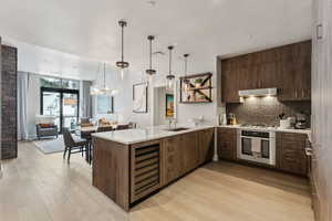 Kitchen with kitchen peninsula, sink, wine cooler, and appliances with stainless steel finishes