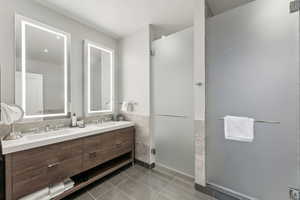 Bathroom featuring tile patterned flooring, vanity, and a shower with door