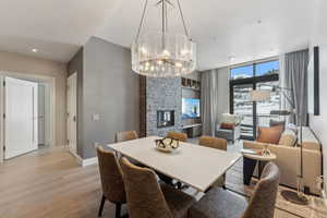 Dining area featuring a notable chandelier, light hardwood / wood-style floors, and a fireplace