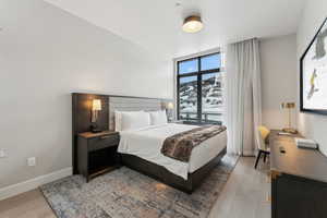 Bedroom featuring a mountain view, expansive windows, and light hardwood / wood-style floors