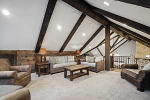 Carpeted living room featuring beamed ceiling, a chandelier, and high vaulted ceiling