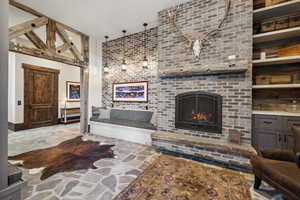 Living room featuring built in shelves, beamed ceiling, and a brick fireplace