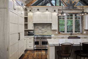 Kitchen featuring light stone countertops, a breakfast bar, pendant lighting, and range with two ovens