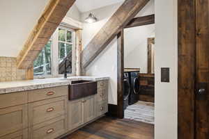 Kitchen with decorative backsplash, dark wood-type flooring, sink, separate washer and dryer, and lofted ceiling