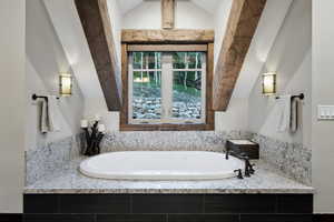 Bathroom with a relaxing tiled tub and vaulted ceiling