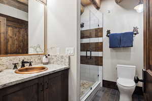 Bathroom featuring beam ceiling, walk in shower, tasteful backsplash, toilet, and vanity