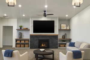 Carpeted living room with a stone fireplace, recessed lighting, and ceiling fan
