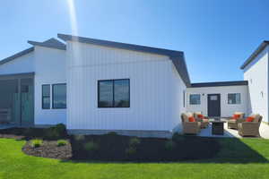 Back of property featuring an outdoor living space with a fire pit, a patio area, and a yard