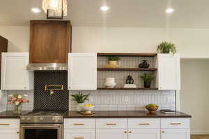 Kitchen featuring backsplash, high end stove, white cabinetry, and recessed lighting