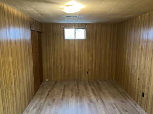 Spare room with light wood-type flooring and wood walls