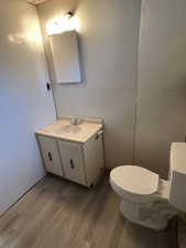 Bathroom featuring vanity, wood-type flooring, and toilet