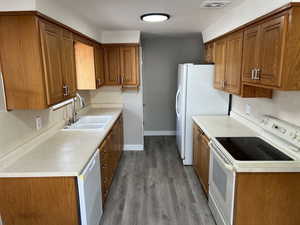 Kitchen with sink, light hardwood / wood-style floors, and white appliances