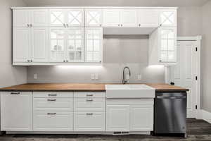 Kitchen with butcher block counters, white cabinetry, sink, and dishwasher