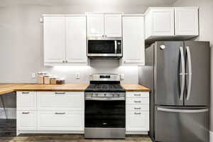 Kitchen featuring stainless steel appliances, white cabinetry, and butcher block counters