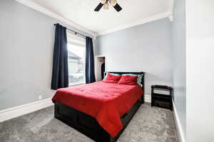 Carpeted bedroom featuring ceiling fan and crown molding