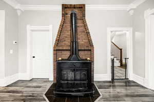 Interior details with hardwood / wood-style flooring, a wood stove, and crown molding