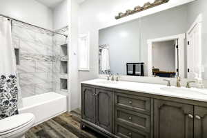 Full bathroom with hardwood / wood-style flooring, vanity, shower / bath combination with curtain, and toilet