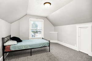 Bedroom featuring a textured ceiling, carpet floors, and lofted ceiling