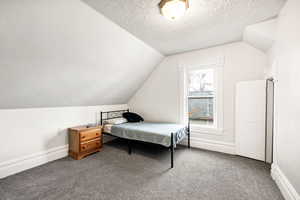 Bedroom featuring a textured ceiling, carpet floors, and vaulted ceiling