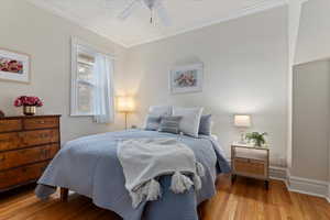 Bedroom with ceiling fan, crown molding, light hardwood / wood-style floors, and a textured ceiling