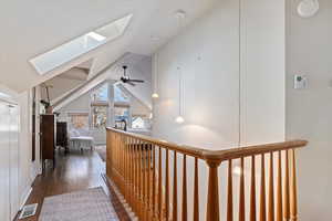 Hallway with dark hardwood / wood-style flooring and lofted ceiling with skylight