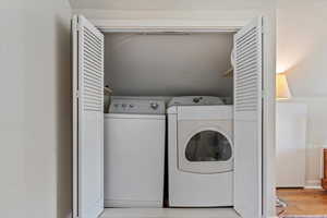 Washroom with washer and dryer and light wood-type flooring