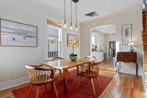 Dining space with light hardwood / wood-style floors and crown molding