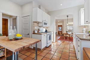 Kitchen featuring white cabinets, sink, white appliances, and hanging light fixtures