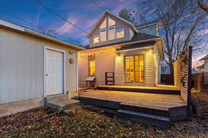 Back house at dusk featuring a wooden deck