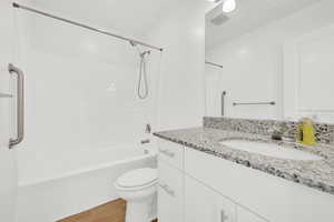 Full bathroom with shower / tub combination, vanity, wood-type flooring, and toilet