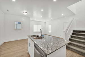 Kitchen featuring sink, a center island with sink, light hardwood / wood-style flooring, dishwasher, and white cabinetry