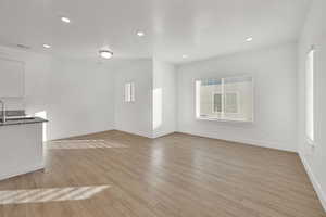 Unfurnished living room featuring sink and light hardwood / wood-style floors