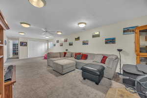 Carpeted living room featuring a textured ceiling and ceiling fan