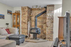 Workout room with carpet, a wood stove, and a textured ceiling