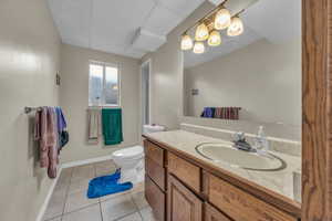 Bathroom featuring a paneled ceiling, vanity, toilet, and tile patterned floors