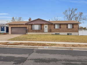 Single story home with a garage and a front lawn